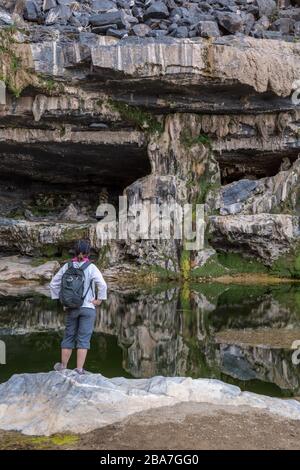 Jebel Shams, Oman. Une piscine d'eau et une petite chute d'eau dans les montagnes, à proximité de la randonnée connue sous le nom de balconnet Walk. Un randonneur féminin regarde. Banque D'Images