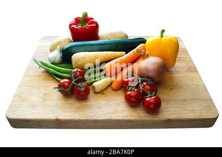 Sélection de légumes sur une planche à découper en bois avec un fond isolé Banque D'Images
