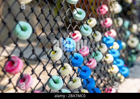 Décorations douces colorées et rondes accrochées sur la clôture en filet près du chemin en bois en Thaïlande. Le centre de la photo est mis au point par l'appareil photo Banque D'Images