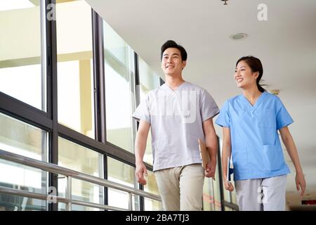 de jeunes thérapeutes asiatiques heureux de marcher parler dans le couloir de la maison de soins infirmiers Banque D'Images