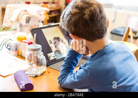 Un enfant qui écoute une grand-mère racontant une histoire via facetime sur ipad pro pendant la quarantaine du coronavirus covid-19 chez lui, en Hongrie Banque D'Images