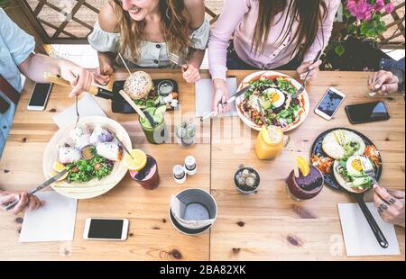 Les jeunes qui mangent du brunch et boivent un bol de smoothie au bar vintage - Les Gens Heureux qui ont un déjeuner sain et bavardent dans le restaurant branché - Food tr Banque D'Images