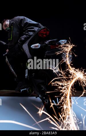 mise au point sélective d'un joueur mixte de cyberpunk de course dans un masque de moto avec des étincelles en noir et blanc Banque D'Images