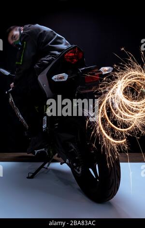 mise au point sélective d'un dangereux joueur de cyberpunk mixte de course dans un masque à moto près d'étincelles en noir et blanc Banque D'Images