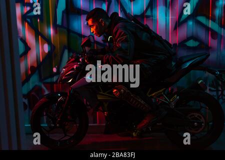 profil du joueur de cyberpunk de course mixte à moto dans la rue avec graffiti Banque D'Images