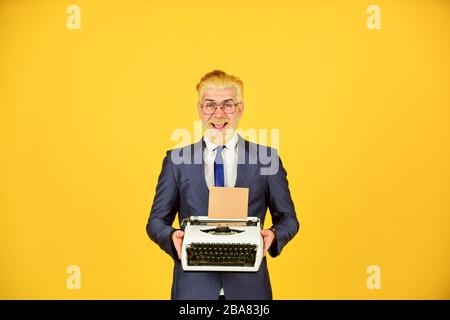 Les vieux habitudes de l'auteur de bâton. Magasin de marchandises d'occasion. Objets anciens du vendeur. Connaisseur des valeurs vintage. Machine à écrire vintage. Les hommes d'affaires utilisent la technologie rétro. Homme mûr teint les cheveux de barbe fond jaune. Banque D'Images
