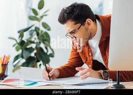Mise au point sélective d'esquisses créatives de concepteur de conception d'expérience utilisateur près de l'écran d'ordinateur et des cercles de couleur sur la table Banque D'Images