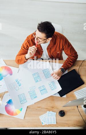 Vue en hauteur du concepteur pensif travaillant avec des modèles de conception d'expérience utilisateur sur une table Banque D'Images