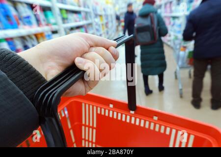 la main de l'homme tient un panier vide dans un supermarché. Le concept d'achat de produits. Banque D'Images