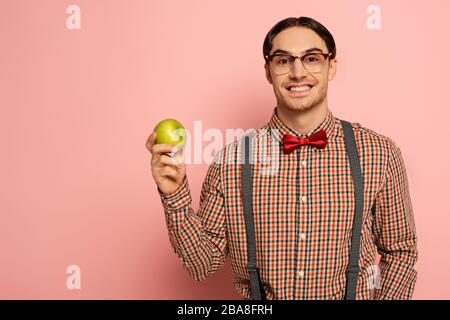 gai homme nerd dans des lunettes tenant la pomme sur le rose Banque D'Images