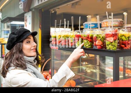 Belle jeune fille montre différents fruits tranchés dans des tasses en plastique a vendu un magasin de véhicule de décrochage à Istanbul, Turquie.Traveler femme style de vie concept. Banque D'Images