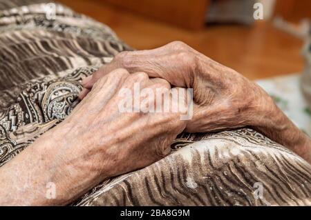 Gros plan sur les mains d'une femme âgée posée sur son lit. Banque D'Images