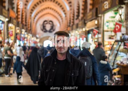 Portrait de beau homme dans des vêtements modernes tendance se dresse parmi les gens dans le grand bazar, Istanbul, Turquie. Banque D'Images