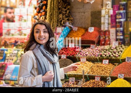 Belle femme montre des herbes séchées ou des fleurs en se tenant devant un stand d'épices vendu sur le stand en Egypte Bazar à Eminonu, Istanbul, Turquie Banque D'Images