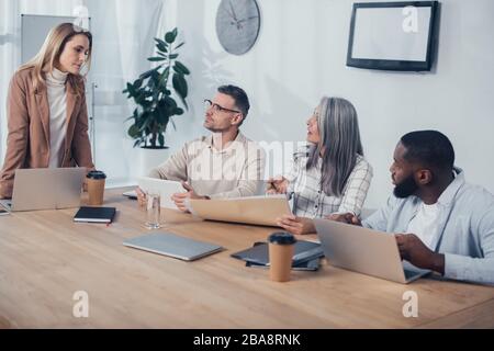 des collègues multiculturels parlent lors d'une réunion dans une agence créative Banque D'Images