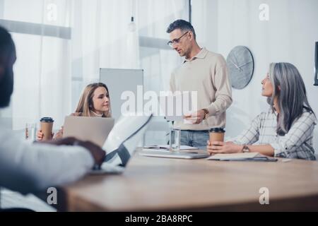 objectif sélectif des collègues multiculturels qui parlent et font de la paperasserie dans l'agence créative Banque D'Images