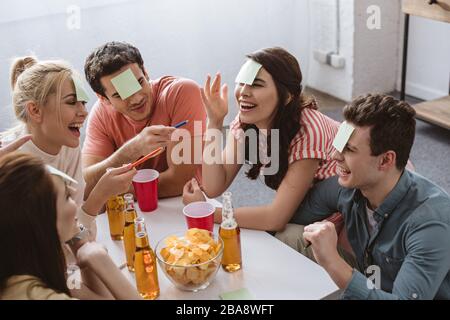 homme et femme joyeux pointant avec des stylos tout en jouant au jeu de nom avec des amis Banque D'Images