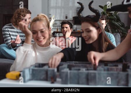 KIEV, UKRAINE - 27 JANVIER 2020: Foyer sélectif des filles heureuses dans les costumes de fées jouant le jeu de table de labyrinthe près d'amis Banque D'Images