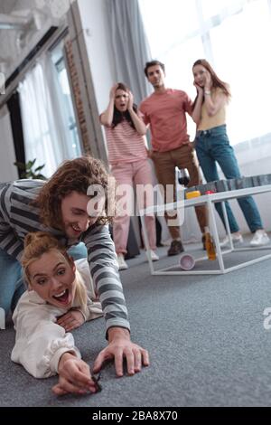 KIEV, UKRAINE - 27 JANVIER 2020: Foyer sélectif de type essayant de prendre la figurine jouet de fille posée sur le sol près d'amis choqués se tenant près de labyr Banque D'Images