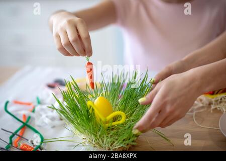 Gros plan photo des filles mettant la carotte à la main au panier de pâques Banque D'Images