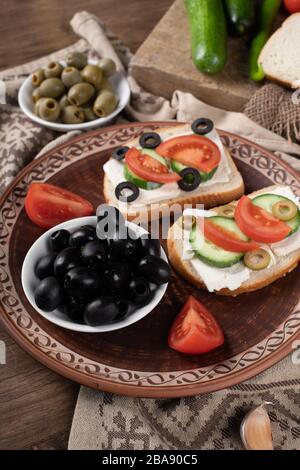 Olives noires dans un bol blanc avec sandwichs Banque D'Images