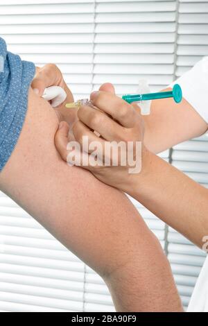 L'homme reçoit l'injection de vaccin contre la grippe Coronavirus COVID-19 avec une seringue à l'hôpital de sa femme médecin Banque D'Images