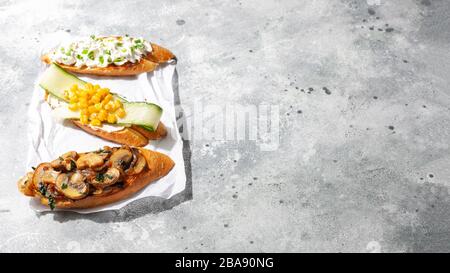 Assortiment de bruschetta ou tapas avec différentes garnitures sur fond de béton.apéritif italien sandwich toast ouvert aux champignons,concombre,maïs Banque D'Images