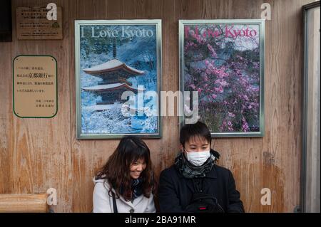 24.12.2017, Kyoto, Japon, Asie - UN jeune couple est assis sous deux affiches publicitaires à un arrêt de bus qui annoncent pour la ville avec le slogan I Love Ky Banque D'Images