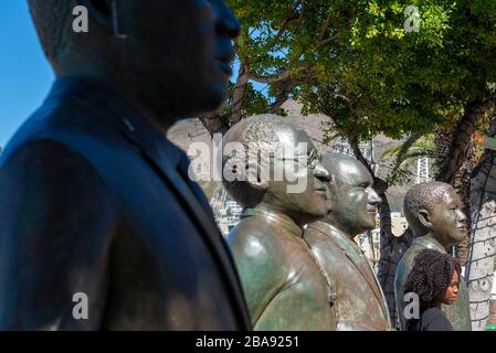 Fille noire debout avec les statues des quatre lauréats du prix Nobel de la paix du pays sur la place Nobel, V&A Waterfront, le Cap, Afrique du Sud Banque D'Images