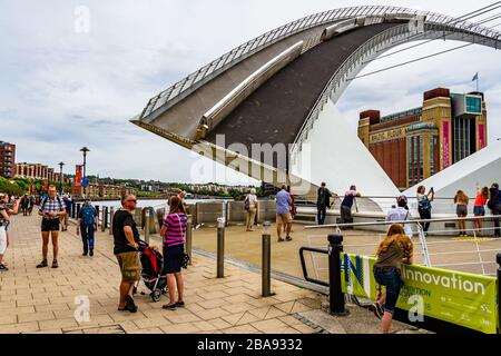 Gateshead Millennium Bridge, un pont inclinable, levé pour laisser passer les bateaux pendant que les gens attendent et regardent. Newcastle upon Tyne, Royaume-Uni. Août 2018. Banque D'Images