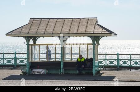 Brighton Royaume-Uni 26 mars 2020 - un sans-abri est assis dans un refuge de bord de mer de Brighton le troisième jour des gouvernements ont verrouillé des restrictions pendant la crise pandémique de Coronavirus COVID-19 . Crédit: Simon Dack / Alay Live News Banque D'Images