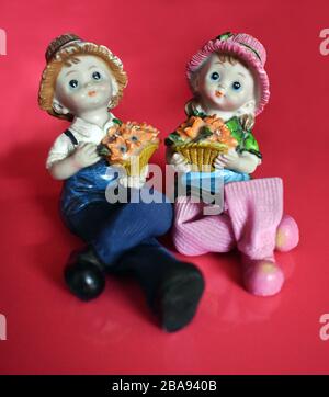 Bonne Saint Valentin. Couple Doll assis et tenant bouquet sur fond rouge Banque D'Images