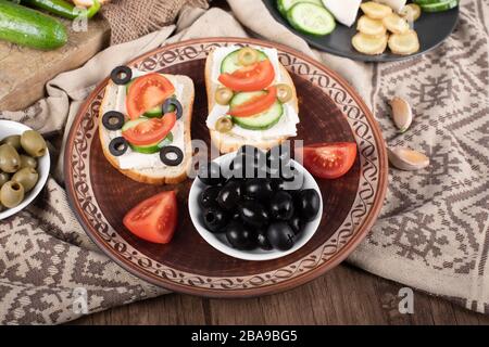 Olives noires marinées avec mini-sandwichs dans un plateau. Banque D'Images