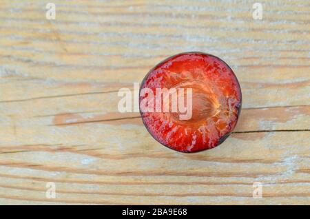 Gros plan de prunes en tranches mûres, foyer sélectif. Prunes fraîches sur table en bois Banque D'Images