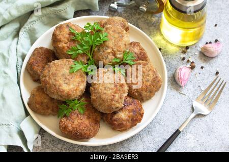 Délicieux côtelettes de viande juteuse maison en assiette, boulettes de viande hachées sur une table en pierre grise. Banque D'Images