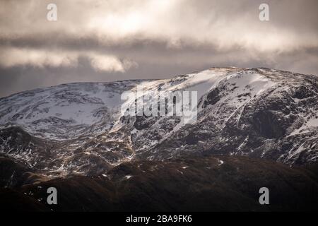 Gros plan du soleil se brisant à travers les nuages sur la neige couvert de la face orientale de Dolywagon Pike, Lake District, Royaume-Uni Banque D'Images