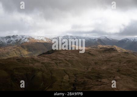 Vue sur les Pikes d'Anglearn, de la place tomba, au soleil se brisant à travers les nuages sur les sommets enneigés de High Street et High Raise, Lake District, Banque D'Images