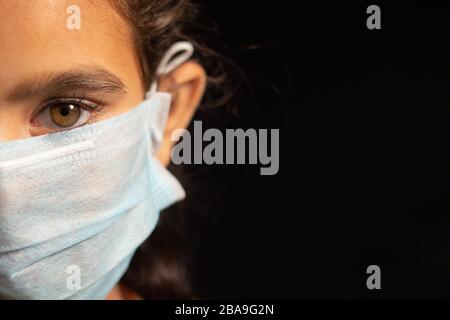 jeune fille enfant avec masque médical portant, protection contre le covid 19 ou la pandémie de coronavirus sur fond noir avec espace de copie. Banque D'Images