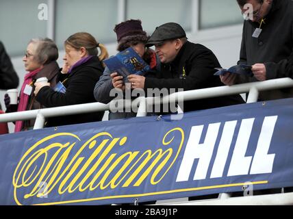 Les amateurs de course étudient le formulaire sur un balcon à l'hippodrome de Kempton Park Banque D'Images