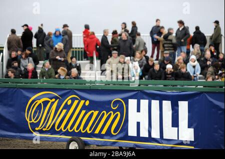 Les amateurs de course sont vus au-delà de la signalisation de William Hill à l'hippodrome de Kempton Park Banque D'Images