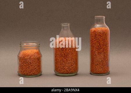 Lentilles rouges dans des pots en verre avec lentilles, fond brut Banque D'Images