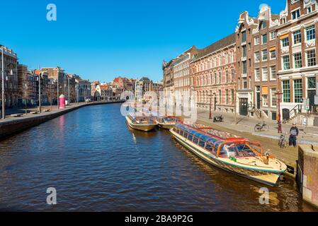 Groupe de bateaux de visite vides amarrés dans un canal d'Amsterdam Pays-Bas en raison de l'éclosion de coronavirus Banque D'Images