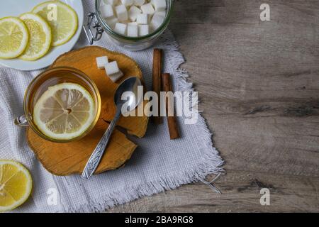 Tasse transparente en verre avec porte-thé à la menthe sur un support en bois, à côté d'un bol à sucre avec des cubes de sucre, du citron en tranches et une cuillère Banque D'Images