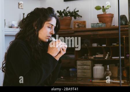 Portrait de profil d'une artiste féminine travaillant sur une petite bijouterie en studio Banque D'Images