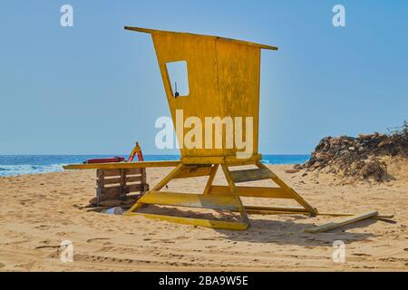 Refuge de maître-nageur jaune sans gardien à côté de la montagne de pierres et fond de la mer sur une journée bleue et claire à Corralejo, Fuerteventura, Canary I Banque D'Images