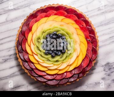 Tarte aux fruits arc-en-ciel sur un plateau de pâtisserie en marbre Banque D'Images