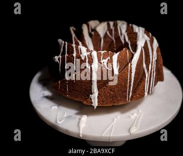 Gâteau de citrouille à motif tourbillon sur un présentoir à gâteaux en marbre sur fond noir Banque D'Images