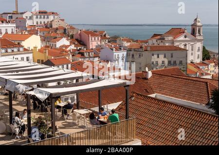 Lisbonne, Portugal 8 mars 2020: Les gens qui ont un dring à un bar avec terrasse avec horizon de Lisbonne en arrière-plan Banque D'Images