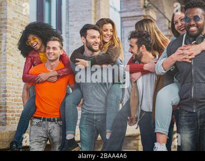 Quatre couples multiraciaux s'amusant sur le dos sous l'arcade en ville le matin. Les élèves s'amuser dans la ville. Banque D'Images