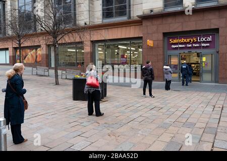 Glasgow, Écosse, Royaume-Uni. 26 mars 2020. Vues depuis le centre-ville de Glasgow jeudi pendant la troisième journée du confinement de Covid-19 sanctionné par le gouvernement. La ville est largement déserte. Seuls les magasins de proximité et de restauration sont ouverts. Sur la photo, les clients font la queue en utilisant la distance sociale pour entrer dans le supermarché local de Sainsburys en une seule fois. Iain Masterton/Alay Live News Banque D'Images